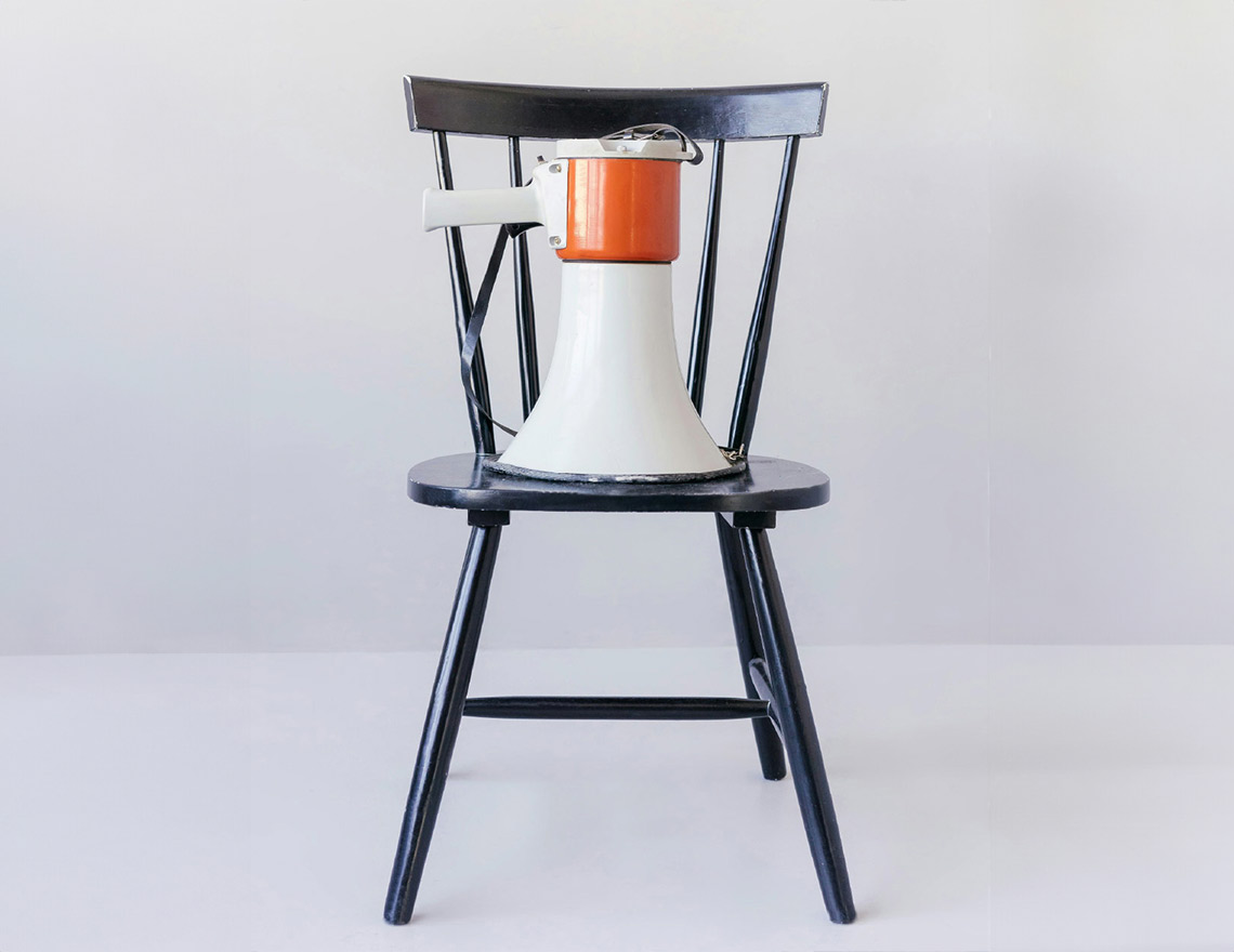 white and red megaphone resting onto of a black wooden chair