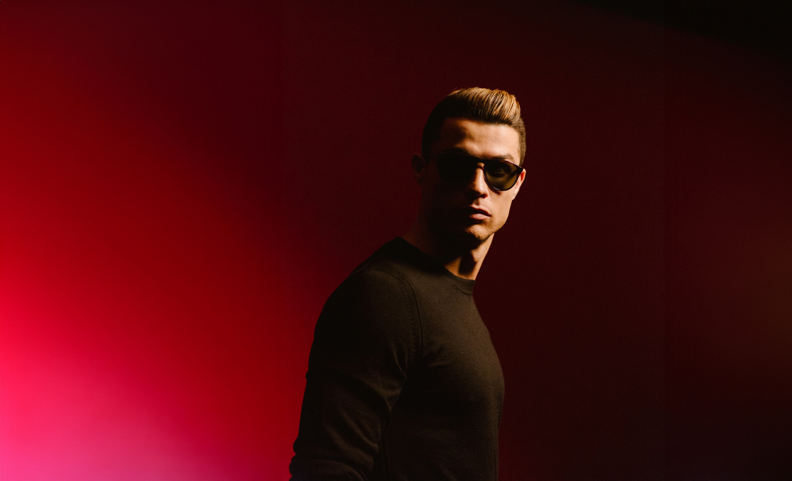 Cristiano Ronaldo in black sunglasses with a red background